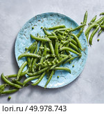 Pear sticks - organic green vegetables for preparing vegetarian salad on a blue plate on a gray table. Natural vegetarian detox dieting. Flat lay. Freshly picked natural green peas with sticks on a blue ceramic plate on a gray marble background. Стоковое фото, агентство Ingram Publishing / Фотобанк Лори