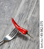 Fresh red cayenne hot pepper on a metal fork on wooden gray background with copy space. Red hot chilli on a metal fork on wooden background. Стоковое фото, агентство Ingram Publishing / Фотобанк Лори