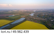 Panoramic view from the drone, aerial photography of the landscape with abstract agricultural fields with rape crops and other agricultural crops and prepared for sowing the soil, the infrastructure of the village with rivers and lakes.. Aerial view from the drone, bird’s eye view abstract geometric forms of agricultural fields with crops, rural development of villages, lakes and rivers on a summer evening at sunset. Стоковое фото, агентство Ingram Publishing / Фотобанк Лори