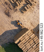 Aerial view from drone into the stack of straw after harvesting the grain. Natural ecological fuel and fertilizers for agricultural work.. The loader stacks bales of straw into the stack after harvesting the grain. Top view. Стоковое фото, агентство Ingram Publishing / Фотобанк Лори