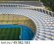 KIEV, UKRAINE - July 19, 2018. Birds eye view from drone of the stadium cover structure - National Sports Complex Olimpiysky at summer sunset. Abstract architecture photo. Construction of the stadium roof.. KYIV, UKRAINE - July 19, 2018. Aerial view from drone of construction of the stadium cover, green football field, tribunes of NSC Olimpiysky. Редакционное фото, агентство Ingram Publishing / Фотобанк Лори