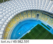 KIEV, UKRAINE - July 19, 2018. Panoramic view from drone of the stadium cover structure -National Sports Complex Olimpiysky. Elements of the stadium construction. Abstract architecture photo.. KYIV, UKRAINE - July 19, 2018. National Sports Complex Olympic NSC Olimpiysky. Aerial view from drone of construction of the stadium cover, green football field, tribunes. Редакционное фото, агентство Ingram Publishing / Фотобанк Лори