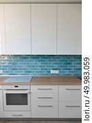Part of the kitchen with hob, oven and brown top in white blue tones. Kitchen with kitchen appliances in modern style. Стоковое фото, агентство Ingram Publishing / Фотобанк Лори