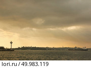 View of the old historical building with mosques, towers, buildings in the eastern style, cargo ships, tugboats in the port on the roadstead on the background of cloudy sky.. Landscape panoramic view from the sea to the historical part of Istanbul, Turkey. Стоковое фото, агентство Ingram Publishing / Фотобанк Лори
