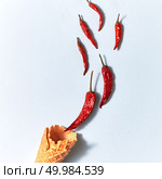 Ice cream waffle cone with red hot dry chili peppers on the gray background. Top view. Red hot dry chili peppers in a wafer cone on gray background, top view. Стоковое фото, агентство Ingram Publishing / Фотобанк Лори