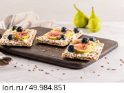 Canape or crostini with multigrain  crispread with cream cheese and fresh fig slices on a wooden board. Delicious appetizer ideal as an aperitif. Стоковое фото, агентство Ingram Publishing / Фотобанк Лори