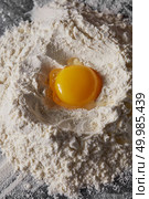 Raw organic egg and white flour on the kitchen table. Preparation for kneading the dough. Raw egg and flour on the kitchen table, staged cooking dough. Стоковое фото, агентство Ingram Publishing / Фотобанк Лори