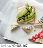 Different kinds of sandwiches with cheese, avocado represented on white chalkboard background for tasting or having break time isolated on table.. Different kinds of sandwiches. Стоковое фото, агентство Ingram Publishing / Фотобанк Лори