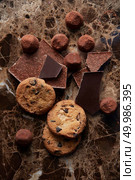 Chocolate chip cookies and different chocolate on cocoa powder and dark marble background. Chocolate chip cookies and chocolates. Стоковое фото, агентство Ingram Publishing / Фотобанк Лори
