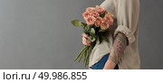 A beautiful bouquet of beige roses cappuccino.The woman is holding flowers in her hand tatoo on a gray background. Mother’s Day, Valentine’s Day. A beautiful bouquet of beige roses cappuccino. Стоковое фото, агентство Ingram Publishing / Фотобанк Лори