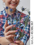Happy Girl holding blue flowers eringium. Holiday, Mother’s Day. Happy girl holding a flower eryngium. Стоковое фото, агентство Ingram Publishing / Фотобанк Лори