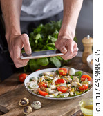 The photo of natural fresh delicious salad in a ceramic plate by mobile smartphone, make a Chef-cooker above a wooden background.. Appetizing healthy salad from organic ingredients in a plate with mens hand making the photo by smartphon on a wooden table. Стоковое фото, агентство Ingram Publishing / Фотобанк Лори