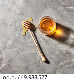 A puddle of honey on the table with glass pot with natural organic dessert on a gray marble table, copy space. Jewish New Year healthy holiday concept. Natural sweet dessert - organic honey in a glass pot with dipper on a gray stone table. Top view. Rosh hashanah jewish holiday. Стоковое фото, агентство Ingram Publishing / Фотобанк Лори