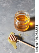 Jewish holiday Rosh Hashanah background with sweet organic honey on a gray concrete background, copy space. Top view. Traditional useful sweetness.. A puddle of honey on the table with glass pot with natural organic dessert on a gray concrete table. Jewish New Year healthy holiday . Стоковое фото, агентство Ingram Publishing / Фотобанк Лори