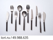 A variety of spoons, knives and forks on a gray background with space for text. Vintage set. Flat lay. Set of vintage metal spoons, forks and knives on a gray background with space for text. Flat lay. Стоковое фото, агентство Ingram Publishing / Фотобанк Лори
