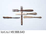 Metal knives with ornaments and forks with wooden handles on a gray background with space for text. Old vintage cutlery set. Flat lay. Composition of metal vintage knives with an ornament and old forks with wooden handles on a gray background with space for text. Flat lay. Стоковое фото, агентство Ingram Publishing / Фотобанк Лори
