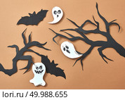 Creative composition of paper with flying bats and ghosts over tree branches on a brown background with space for text. Handcraft layout for Halloween. Flat lay. Paper tree branches flying ghosts and bats on a brown background with space for text. Scary handcraft layout to Halloween. Flat lay. Стоковое фото, агентство Ingram Publishing / Фотобанк Лори