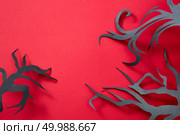 Composition of paper handcraft trees on an red background with space for text. Halloween postcard. Flat lay. Mystical pattern of black paper handcraft trees on an redkground with space for text. Halloween layout. Flat lay. Стоковое фото, агентство Ingram Publishing / Фотобанк Лори