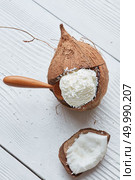 Fresh and tasty Coconut Ice Cream Packed in a coconut shell With a wooden spoon On white wooden background. Delicious vanilla ice cream in coconut. Стоковое фото, агентство Ingram Publishing / Фотобанк Лори