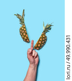 A sign with a woman’s hand fucking and a half pineapple on a blue background with space for text. Flat lay. Creative composition of pineapple slices and a female hand showing the middle finger on a blue background with copy space. Flat lay. Стоковое фото, агентство Ingram Publishing / Фотобанк Лори