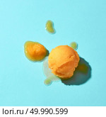 Creative composition of yellow melted ice cream on a blue glass background with hard shadows . Top view. Flat lay of a yellow ice cream scoop and melted ice cream on a blue background with hard shadows. Стоковое фото, агентство Ingram Publishing / Фотобанк Лори