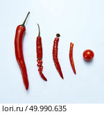 Hot chili pepper chopped whole and pieces on a light background with cherry tomato. The flat lay. sliced chilli cayenne pepper with tomato on a gray background, top view. Стоковое фото, агентство Ingram Publishing / Фотобанк Лори