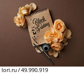 Notepad with a caligraphic text and a frame of flowers on a brown background, Sale concept Black Friday flat lay copy space. notebook with yellow roses. Стоковое фото, агентство Ingram Publishing / Фотобанк Лори
