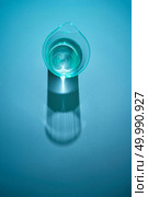 Top view of glass with water on a light blue background and long shadows a paper, place under text.. The glass of transparent water with reflex and shadows on a blue paper background. Стоковое фото, агентство Ingram Publishing / Фотобанк Лори