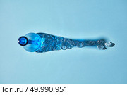 The bottle shadows from pieces of crushed transparent artificial ice cubes and empty blue bottle on a blue background. Top view.. Blue empty bottle with shadows from crushed transparent ice cubes on a blue background. Top view. Стоковое фото, агентство Ingram Publishing / Фотобанк Лори