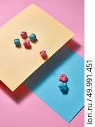 Pink bright macaroons are presented in the form of a triangular pyramid on blue cardboard and one crushed macaroon on a pink paper background with reflection of shadows. Creative composition. composition of colorful macaroons on a blue and yellow papers on pink background. Стоковое фото, агентство Ingram Publishing / Фотобанк Лори