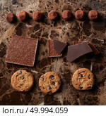 chocolate pieces, truffle candy and cookies on a marble dark background. Chocolate chip cookies and chocolates. Стоковое фото, агентство Ingram Publishing / Фотобанк Лори