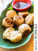 Hoi Jo, Deep Fried Crab Meat Rolls with sweet plum sauce. Thai street food and restaurant cuisine on wooden table. Стоковое фото, агентство Ingram Publishing / Фотобанк Лори