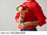 A colorful bouquet of white, red and green flowers Ranunculus is held by a girl with a tattoo on a gray background with copy space. Spring time. Mothers Day. A young girl with a tattoo on a gray background is holding a bright fresh flowers of a Ranunculus. Photo as layout for postcard. Стоковое фото, агентство Ingram Publishing / Фотобанк Лори