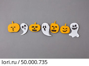 Colorful Halloween handcraft composition with flying floating ghost spirit and smiling yellow pumpkins on a gray paper background, place for text. Flat lay.. Halloween pattern from handmade paper scary ghosts and spirits, yellow pumpkins on a gray paper. Стоковое фото, агентство Ingram Publishing / Фотобанк Лори