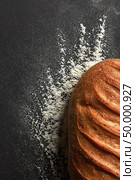 Freshly baked healthy white bread with a pattern of flour on a black background with copy space. Top view. Organic fresh bread with a pattern of flour presented on a black background with space for text. Top view. Стоковое фото, агентство Ingram Publishing / Фотобанк Лори