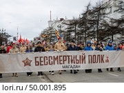 Шествие «Бессмертного полка» в Магадане, 9 мая 2025 года. День Победы. По проспекту Ленина идёт колонна демонстрантов с транспарантом «Бессмертный полк». Участники демонстрации несут красные флаги и портреты ветеранов войны. Празднование 80-летия победы Красной армии и советского народа над нацистской Германией в Великой Отечественной войне 1941–1945 годов. Город Магадан, Магаданская область, Россия. Редакционное фото, фотограф Андрей Степанов / Фотобанк Лори