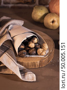 Roasted chestnuts in a paper cone, on a rustic kitchen countertop. Стоковое фото, агентство Ingram Publishing / Фотобанк Лори