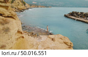 Woman entering the sea via stairs on rocky coast in summer Kefalonia near boat dock. Стоковое AI-видео, аниматор Igor Tichonow / Фотобанк Лори