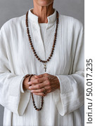 Nun holding rosary beads and praying in white robe. Стоковое AI-изображение, AI-художник Юрий Поздников / Фотобанк Лори