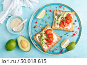 Toasts with feta cheese, tomatoes, avocado, pomegranate, pumpkin seeds and flaxseed sprouts. Diet breakfast. Delicious and healthy food. Flat lay. Top view. Стоковое фото, агентство Ingram Publishing / Фотобанк Лори