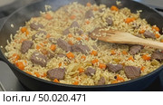 Eastern beef pilaf in a large cauldron, steam rising. A hot dish of rice with meat and vegetables, prepared for a delicious lunch. Стоковое AI-видео, аниматор Ольга Яковенко / Фотобанк Лори