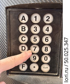 A detailed close-up view of the keyboard with numeric and alphanumeric buttons, ideal for various technical topics. The finger of an unknown person holds his finger near the number 7. Стоковое фото, фотограф worker / Фотобанк Лори