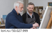 Experienced painter showing young apprentice how to paint on canvas. Стоковое AI-видео, аниматор Юрий Поздников / Фотобанк Лори