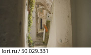Woman walks down stone stairs between whitewashed Mediterranean buildings in Amalfi town Italy. Стоковое AI-видео, аниматор Igor Tichonow / Фотобанк Лори