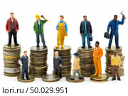 Miniature figures of workers and businessmen on coins reflect the ironic situation: someone is at the top of finance, and someone is barely hanging on - a visual allegory of economic pyramids. Banner. Стоковое AI-изображение, AI-художник Евгений Демидюк / Фотобанк Лори
