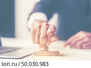 Close-up Of A Person’s Hand Stamping With Approved Stamp On Document At Desk. Стоковое фото, агентство Ingram Publishing / Фотобанк Лори