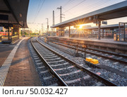 Railway station at sunset. Industrial landscape with railroad, railway platfform, buildings, blue sky with orange sunlight in the evening. Railway junction in summer in Europe. Transportation. Стоковое фото, агентство Ingram Publishing / Фотобанк Лори
