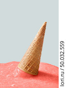 Meltdown of ice cream in a color of the year 2019 Living Coral pantone on a gray background. Falling crispy waffle cone of ice cream. Place for text.. Waffle cone with melted ice cream in a color of the year 2019 Living Coral pantone on a gray background with copy space. Стоковое фото, агентство Ingram Publishing / Фотобанк Лори