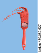 Splashes of paint and brush in color of the year 2019 Living Coral Pantone on a blue background. Place for text.. Paintbrush with liquid paint in a color of the year 2019 Living Coral Pantone in color isolated on a blue background. Стоковое фото, агентство Ingram Publishing / Фотобанк Лори