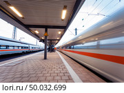 High speed  passenger train on railroad track in motion at sunset. Blurred commuter train. Railway station in Nuremberg, Germany. Industrial landscape. Стоковое фото, агентство Ingram Publishing / Фотобанк Лори